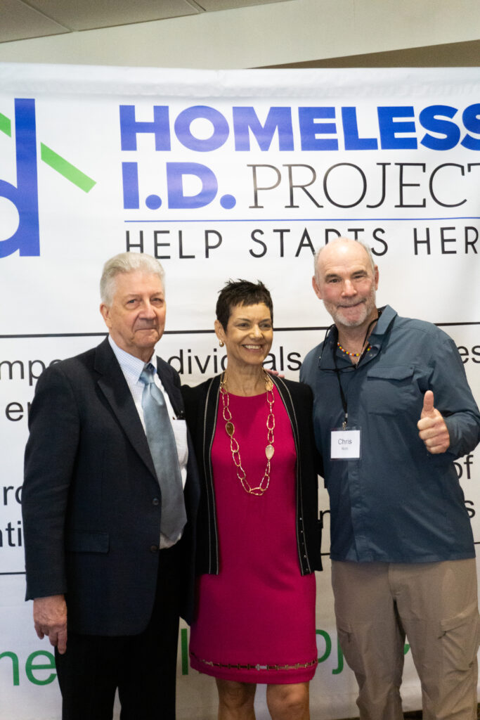 People posing at the HELP STARTS HERE fundraising breakfast on 2025 in front of the Homeless ID Project banenr
